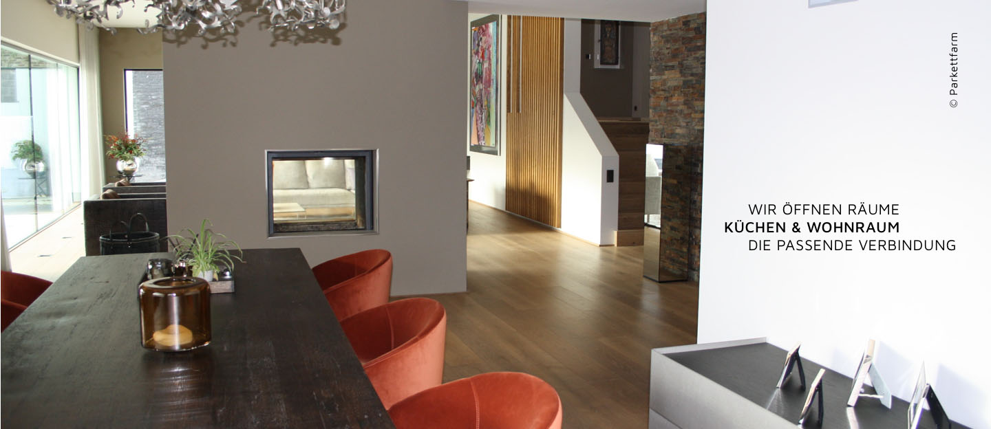 Modernes Esszimmer mit großem Holztisch und orangefarbenen Stühlen, Kamin im Hintergrund, Text auf dem Bild: 'Wir öffnen Räume Küchen & Wohnraum Die passende Verbindung'